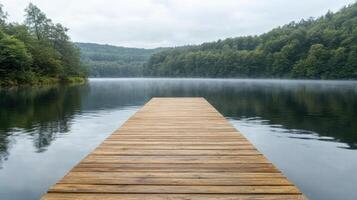 Wooden dock extending into calm water with misty forest backdrop creates serene atmosphere photo