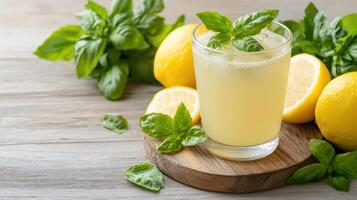 A glass of lemonade with basil leaves on a wooden table photo