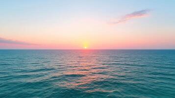 Sunrise over ocean horizon with soft waves reflecting warm colors photo