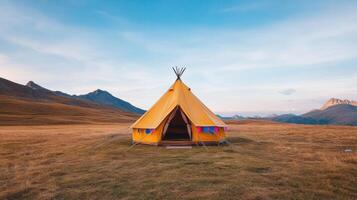Bright yellow tent in vast landscape under clear sky, surrounded by mountains photo