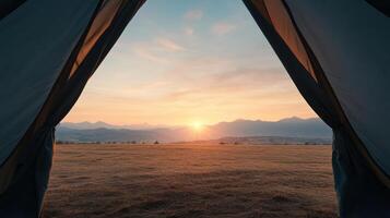 Beautiful sunrise view framed by tent, showcasing mountains and open fields photo