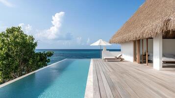 Luxurious ocean villa with thatched roof, wooden deck, and infinity pool overlooking sea photo