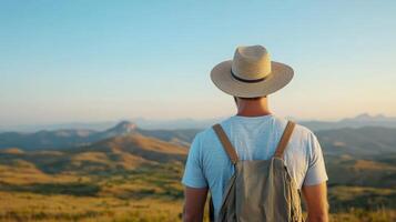 Man with hat and backpack looking at mountains photo