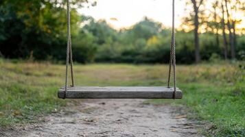 Rustic wooden swing hangs from ropes in serene forest path, illuminated by golden hour light photo
