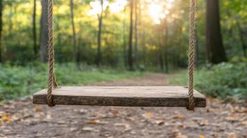 Rustic wooden swing hangs in serene forest path, illuminated by golden hour light photo