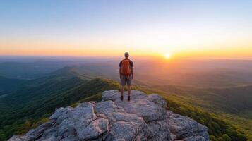 Man standing on top of mountain at sunset photo