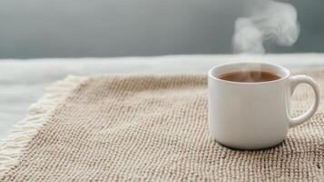 A cup of tea on a table with a blanket photo