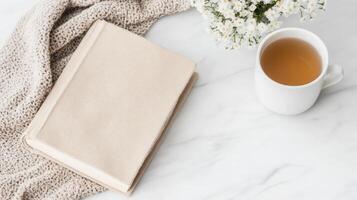 A book, a cup of tea and a bouquet of flowers on a marble table photo