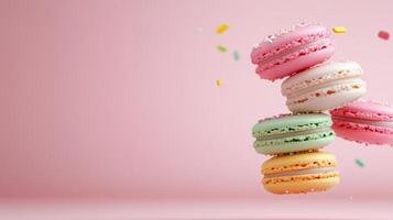 Colorful macarons falling from the air on a pink background photo