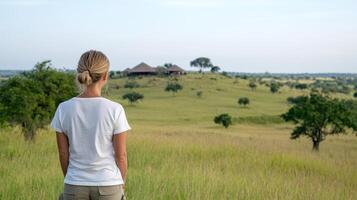 A woman in a white shirt stands in the middle of a field photo