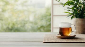 A cup of tea is on a wooden table with a potted plant in the background photo