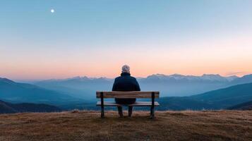 A person sitting on a bench looking at the mountains photo