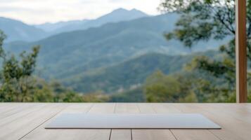 A yoga mat on a wooden floor in front of a mountain view photo