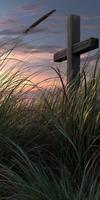 Sunset over tall grass with wooden cross in quiet landscape photo
