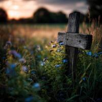 Wooden cross surrounded by wildflowers at sunset in a field photo