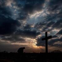 persona en silueta se arrodilla por cruzar a puesta de sol con nubes foto