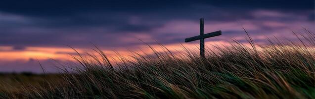 Cross stands tall in grassy field during sunset photo