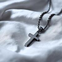 A black cross necklace laying on a white sheet photo