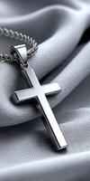 A silver cross necklace on a cloth photo