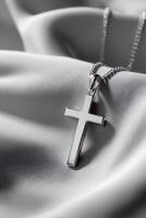 Elegant silver cross pendant on a soft fabric background photo