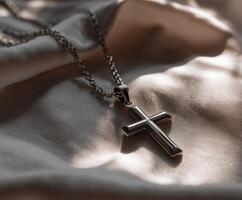 Silver cross necklace on smooth fabric surface photo