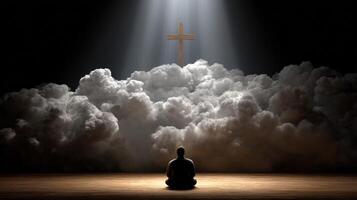 Man meditating under light with a cross in the background photo