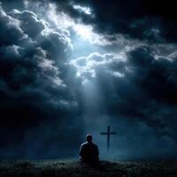Individual prays under dramatic clouds and light beams photo