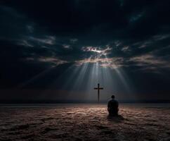 Man meditating on sandy shore under dramatic sky with cross photo