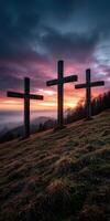 Sunset silhouettes of three wooden crosses on a hillside photo