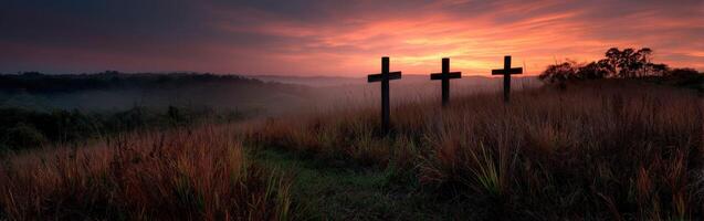 Three crosses in the middle of a field at sunset photo