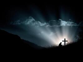 Silhouette of a person praying at a cross during sunset photo