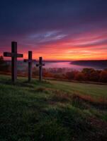 Three wooden crosses sit on a hill overlooking a foggy field photo