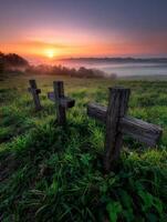 Three wooden crosses in a field at sunrise photo