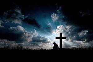Person kneeling in prayer by a cross under dramatic clouds photo