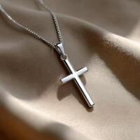 Silver cross pendant displayed on soft fabric photo