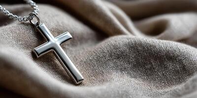 Silver cross pendant resting on beige fabric photo