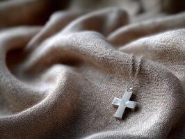 Silvery cross pendant resting on textured fabric photo