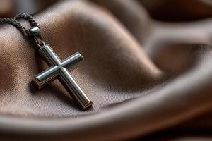 Silver cross pendant resting on smooth fabric surface photo
