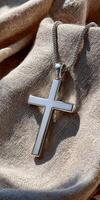 A silver cross pendant on a linen cloth photo