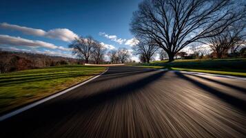Curving road lined with trees against a blue sky photo