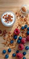 Granola, blueberries, raspberries and yogurt on a wooden table photo