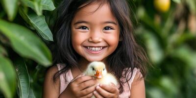 A little girl smiles while holding a duckling photo