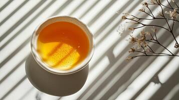 A bowl of orange juice on a table with sunlight photo