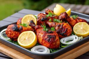 Tandoori chicken legs garnished with lemon and onion rings photo