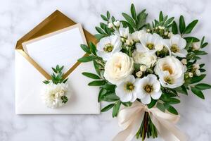Elegant white bouquet with ribbon and blank card with golden envelope laying on marble table photo