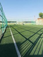 Green artificial turf soccer field with clear blue sky backdrop photo