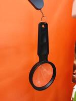 Magnifying glass displayed on bright orange background. photo