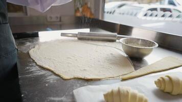 Flour being sprinkled on croissant dough before cutting video