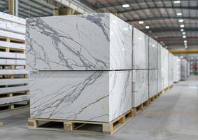 White marble slabs are stacked on pallets inside a spacious warehouse, prepared for transport to various construction sites photo