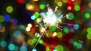 A sparkler is lit up in front of a colorful background video